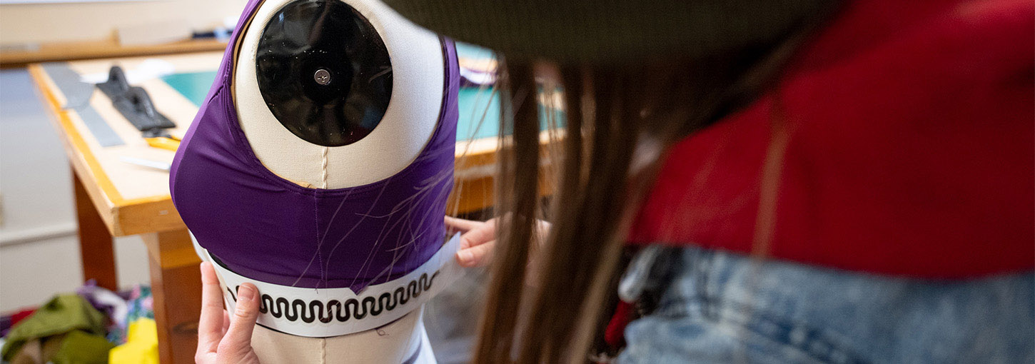 A person holds a flat sensor up to a sports bra on a mannequin.