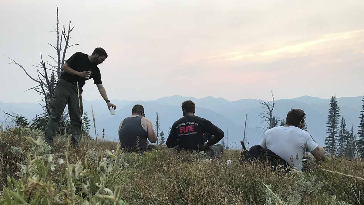 Four firefighters sitting in a field.