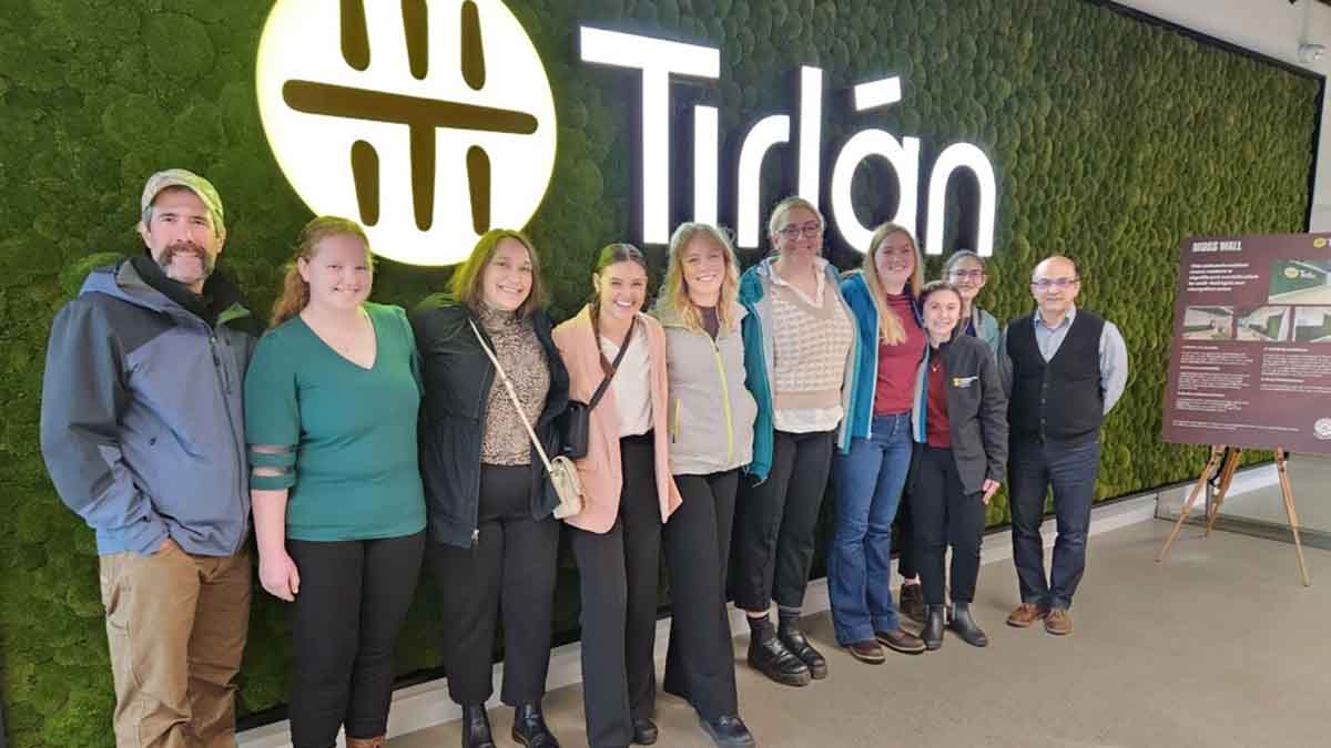 A group of men and women in front of a Tirlan sign in Ireland.