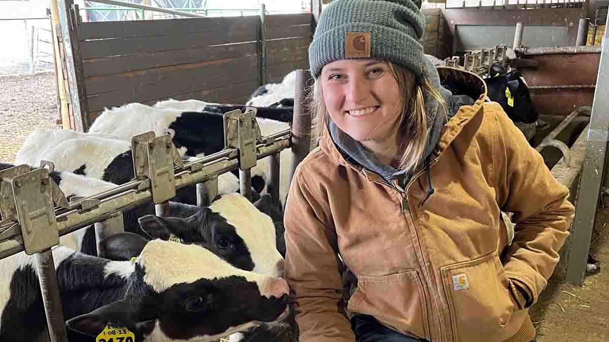 A woman in a barn of cows.