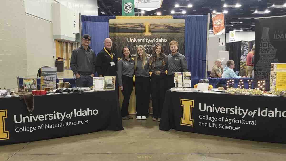 A group of men and women behind two display tables at a conference.