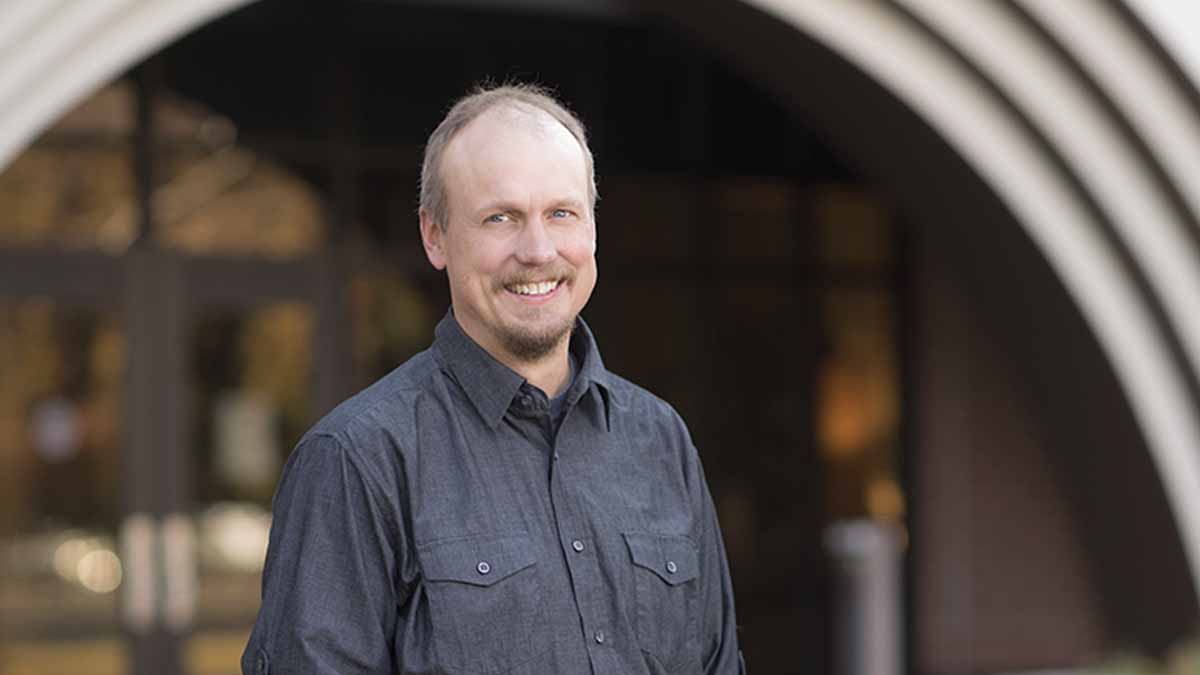 Portrait of a man standing in front of a building entrance.