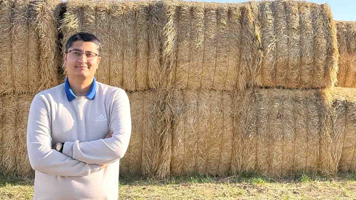 A man standing in front of bails of hay.
