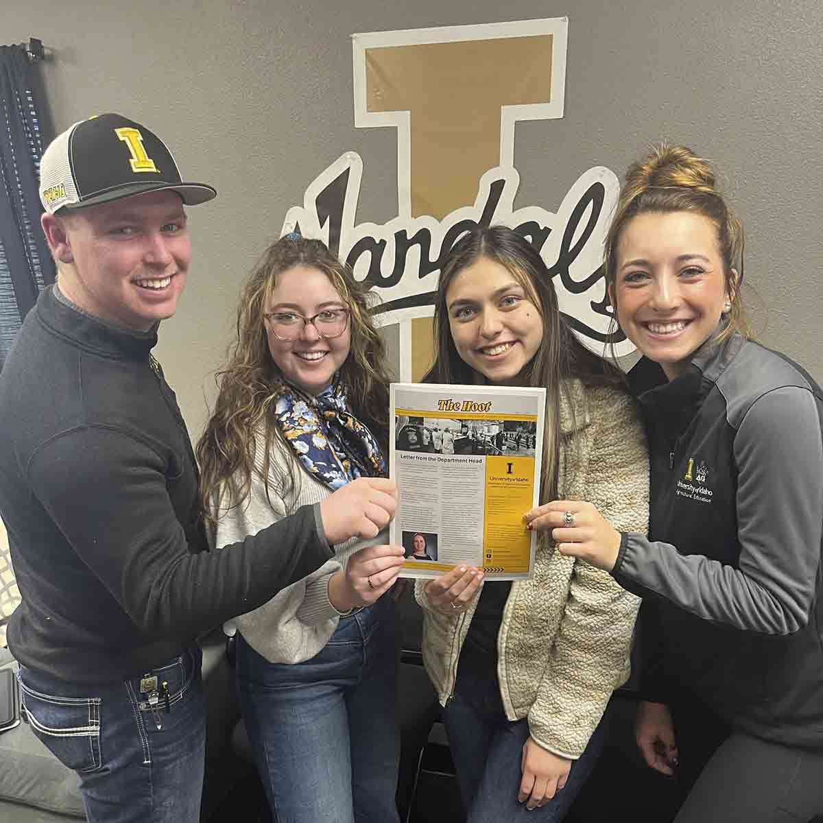 A group holding up a newsletter.