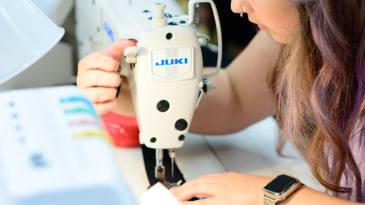 A student works on an industrial lockstitch sewing machine for an interdisciplinary project.