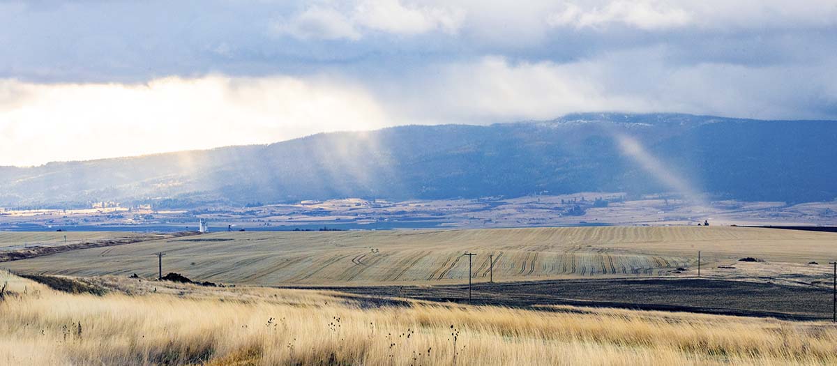 A scenic view of fields and mountain with sun rays coming down through the clouds.