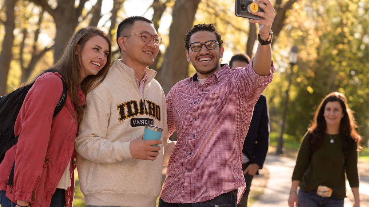 Three students take a selfie on Hello Walk on the University of Idaho campus.