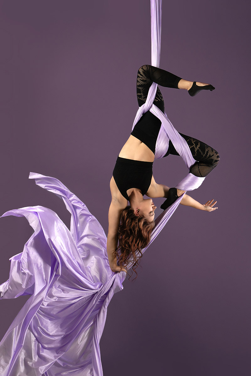 A woman hanging upside down from a silk material