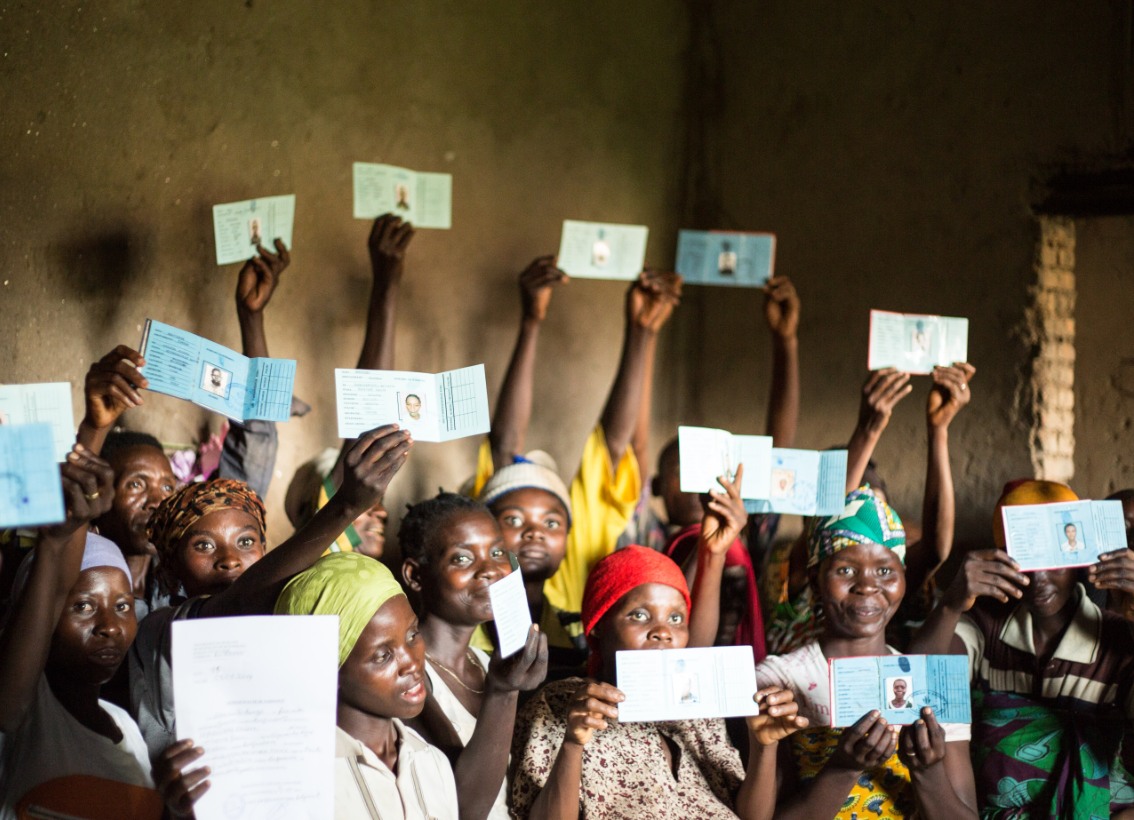 A group of African women hold up their new ID cards