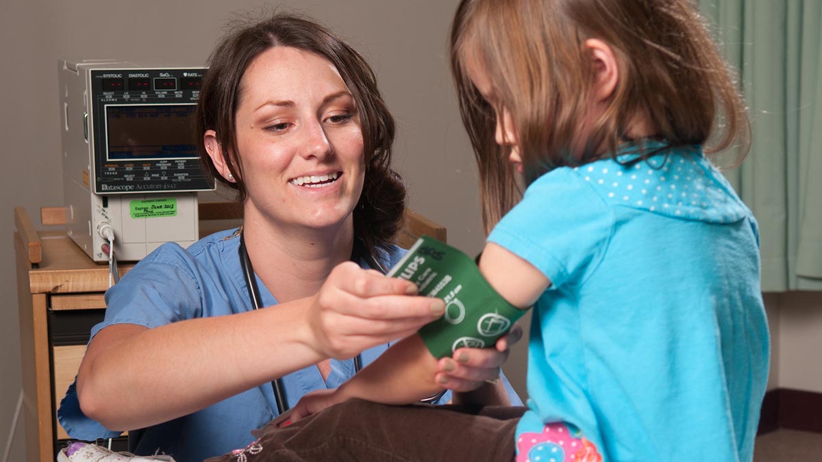 A pre-health student puts a blood pressure cuff on a patient.