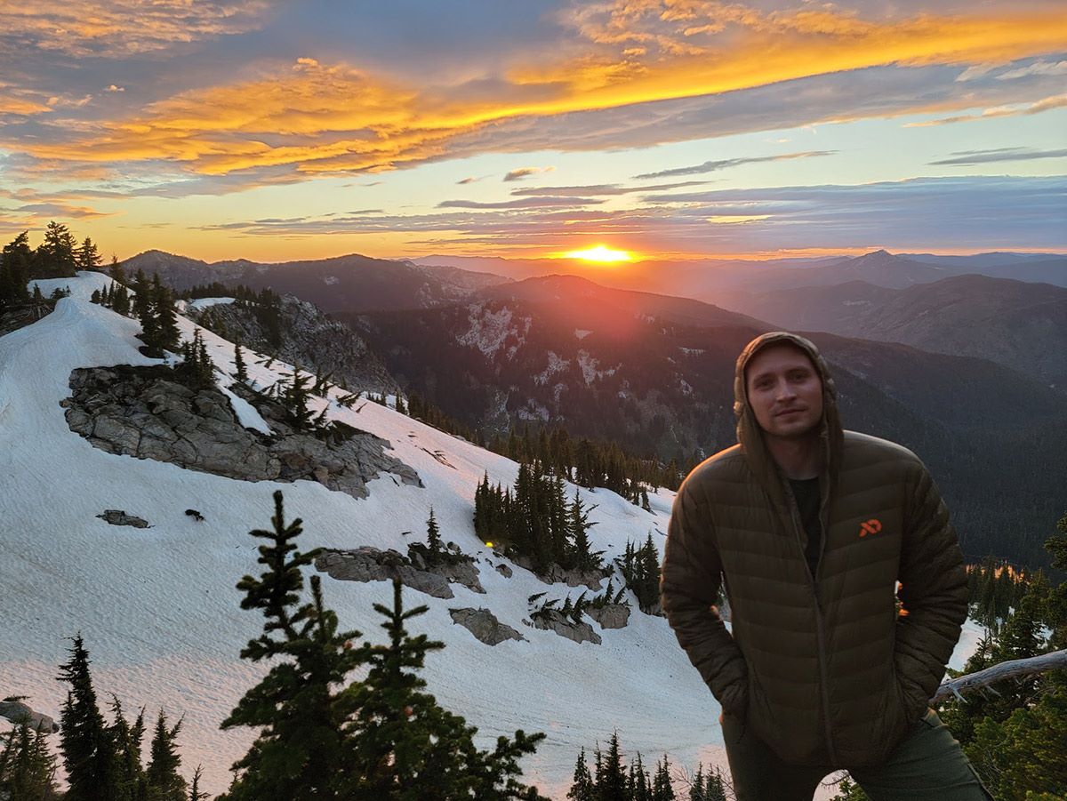Logan Tompkins on a snowy mountain at sunset.