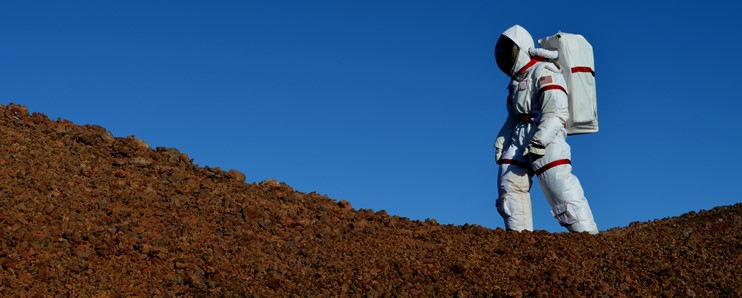 The HI-SEAS space suit walking the rocky landscape.