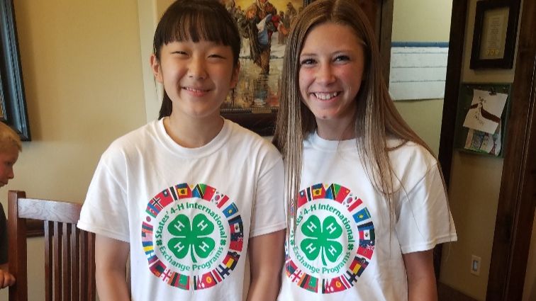 Two teens wear matching shirts with "States' 4-H International Exchange Programs logo.