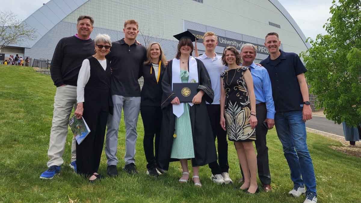 A group photo of men and women surrounding a college graduate.