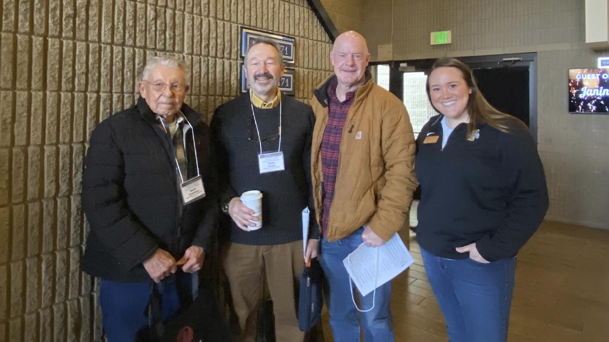 A group of three men and a woman pose for the camera.