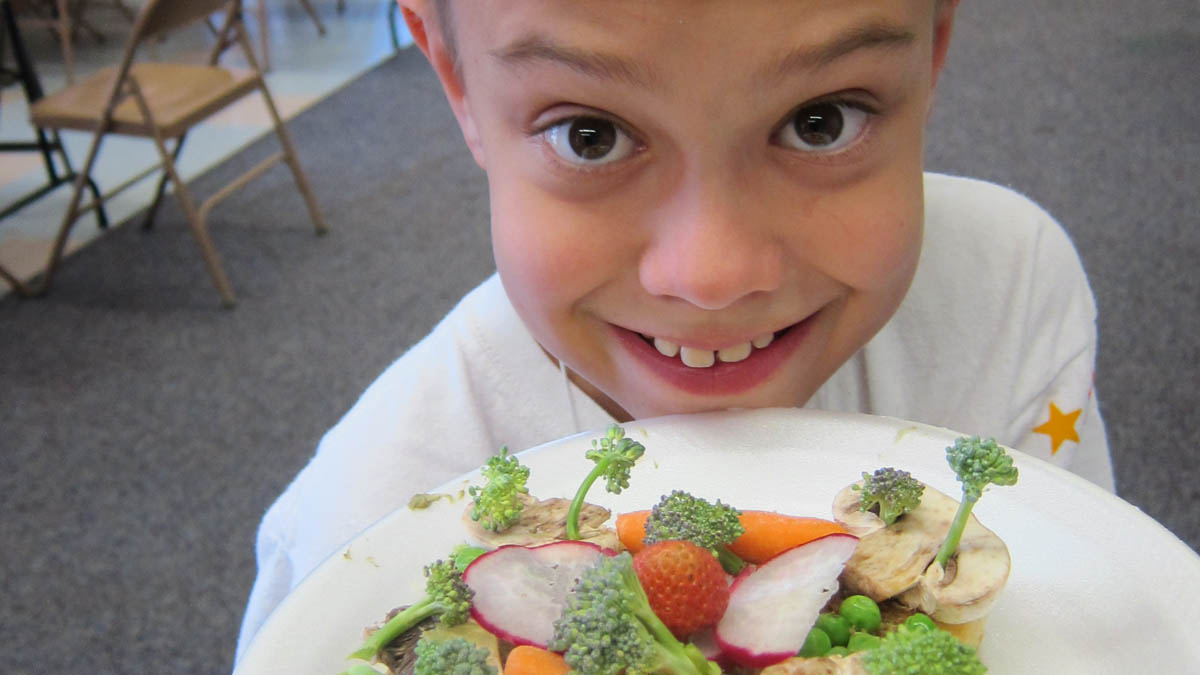 child holding a plate of vegetables that looks like trees, a jungle