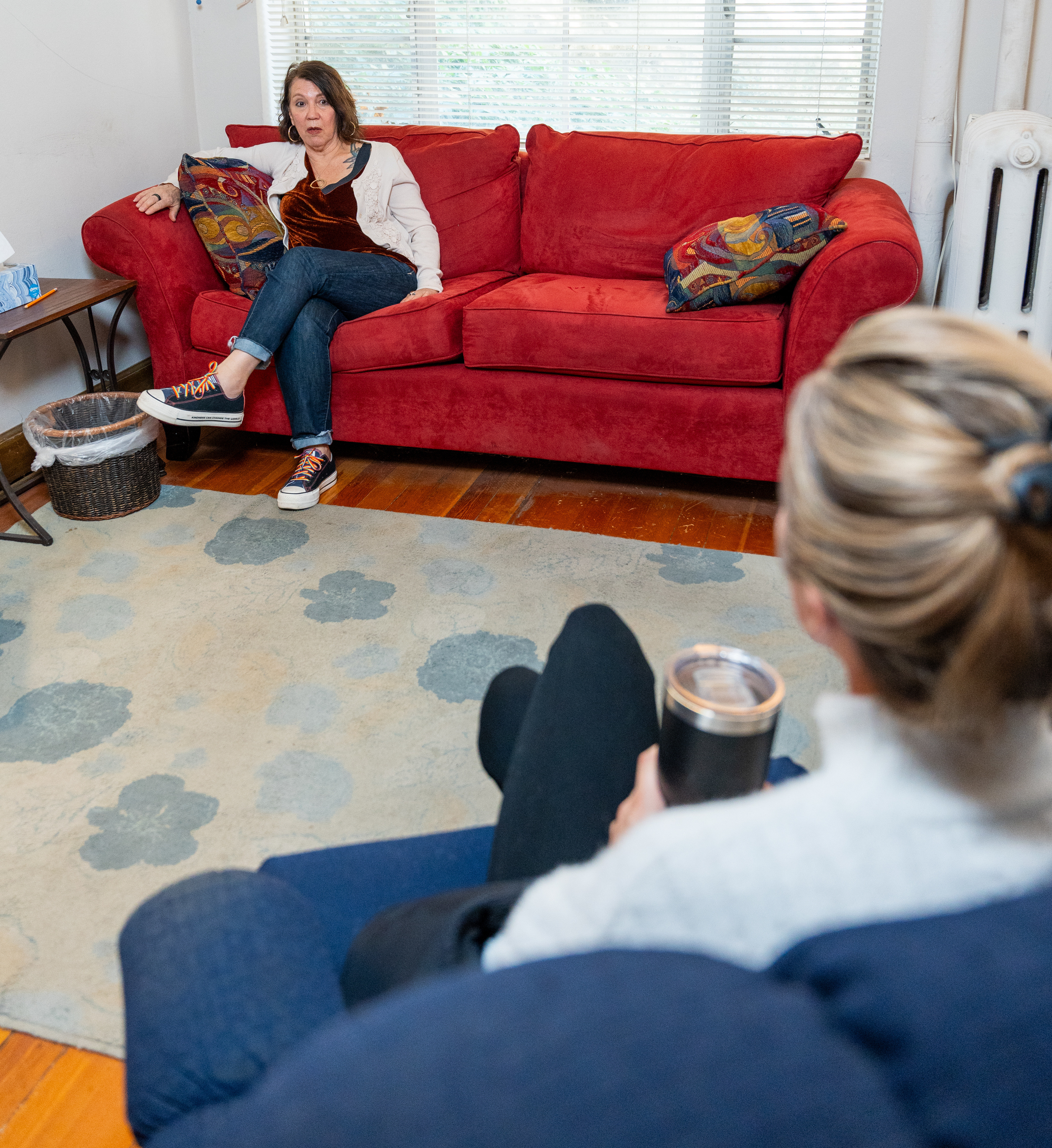 Two women sit on couches and talk.