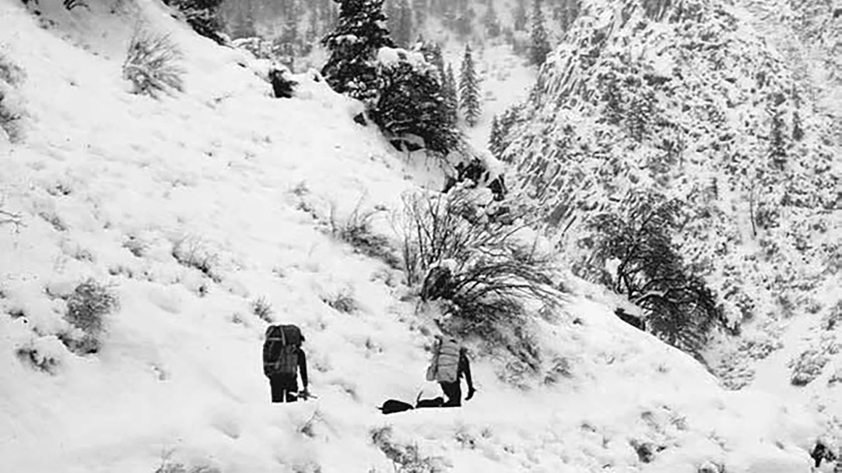 Two people walk through a mountainous landscape. Credit: Maurice Hornocker.