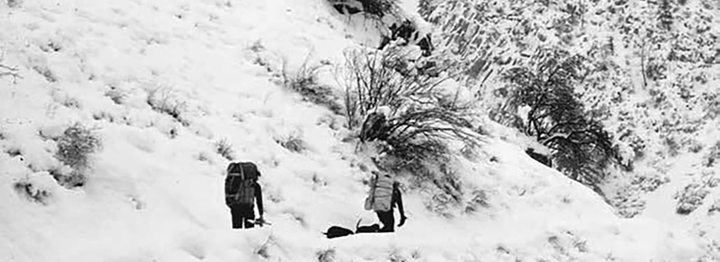 Two people walk through a mountainous landscape. Credit: Maurice Hornocker.