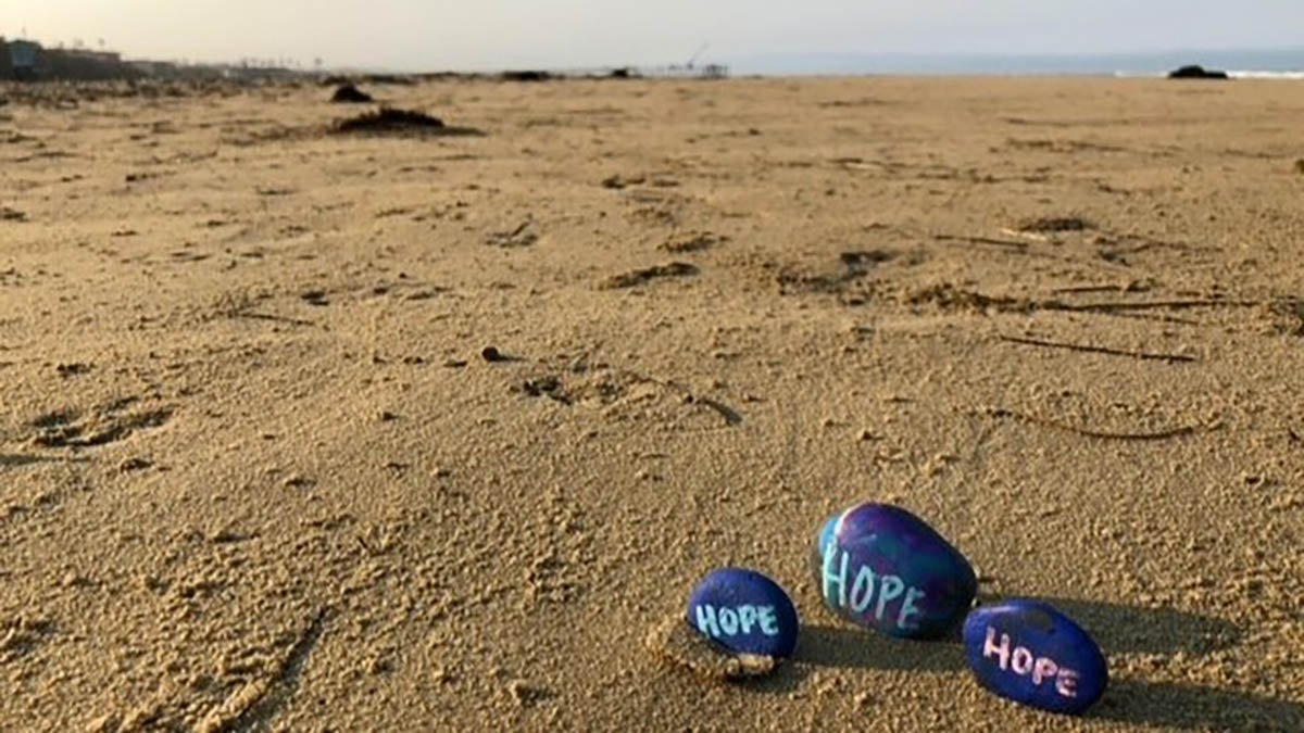 Photo of three rocks on the beach with ocean in background.