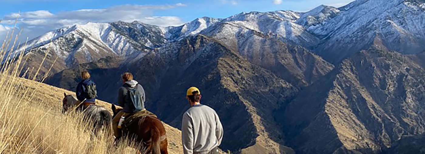 People ride horses in front of mountains. Credit: Andrew Armstrong.