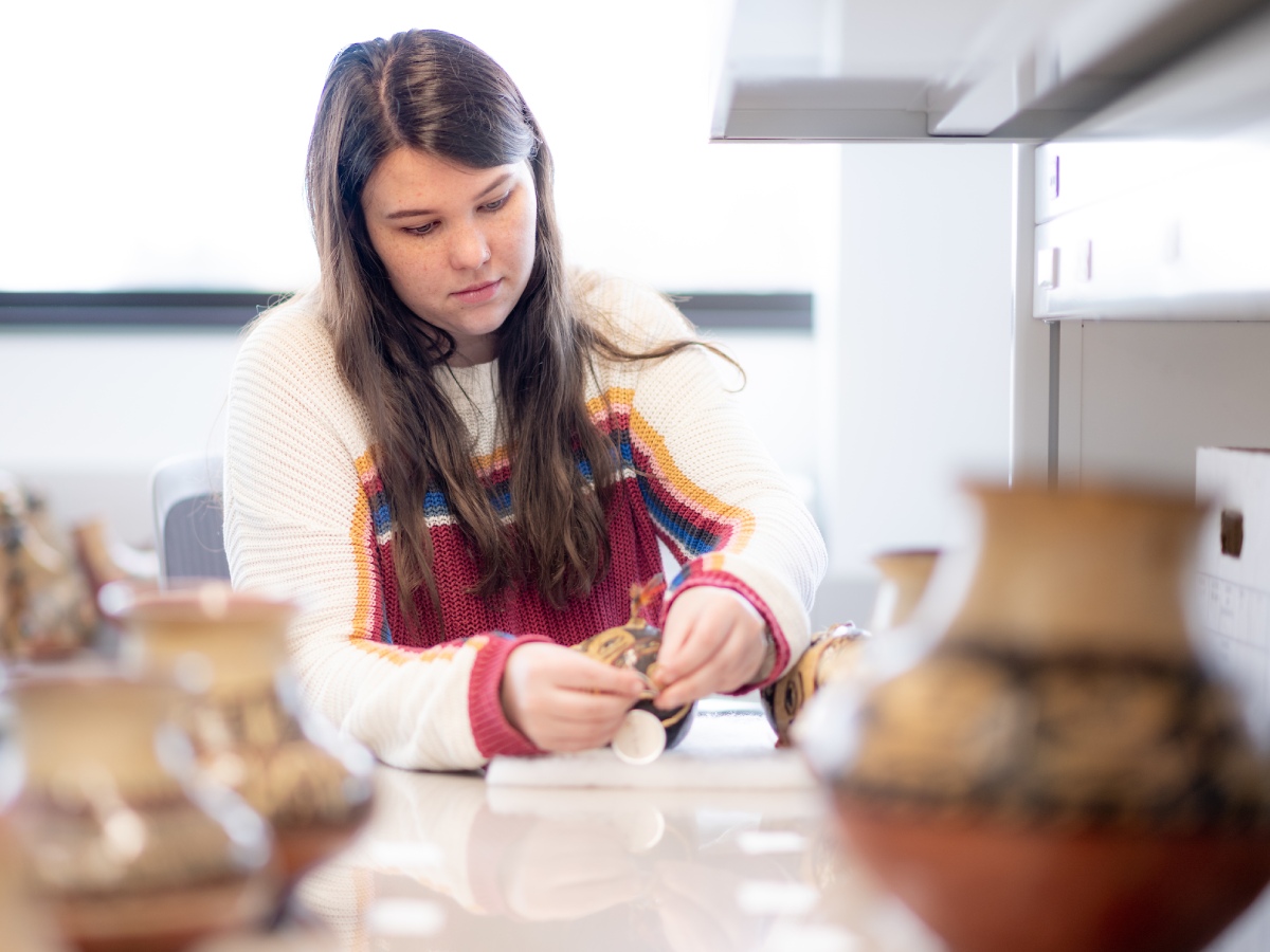 Kristina Cockerille examines a piece of pottery.