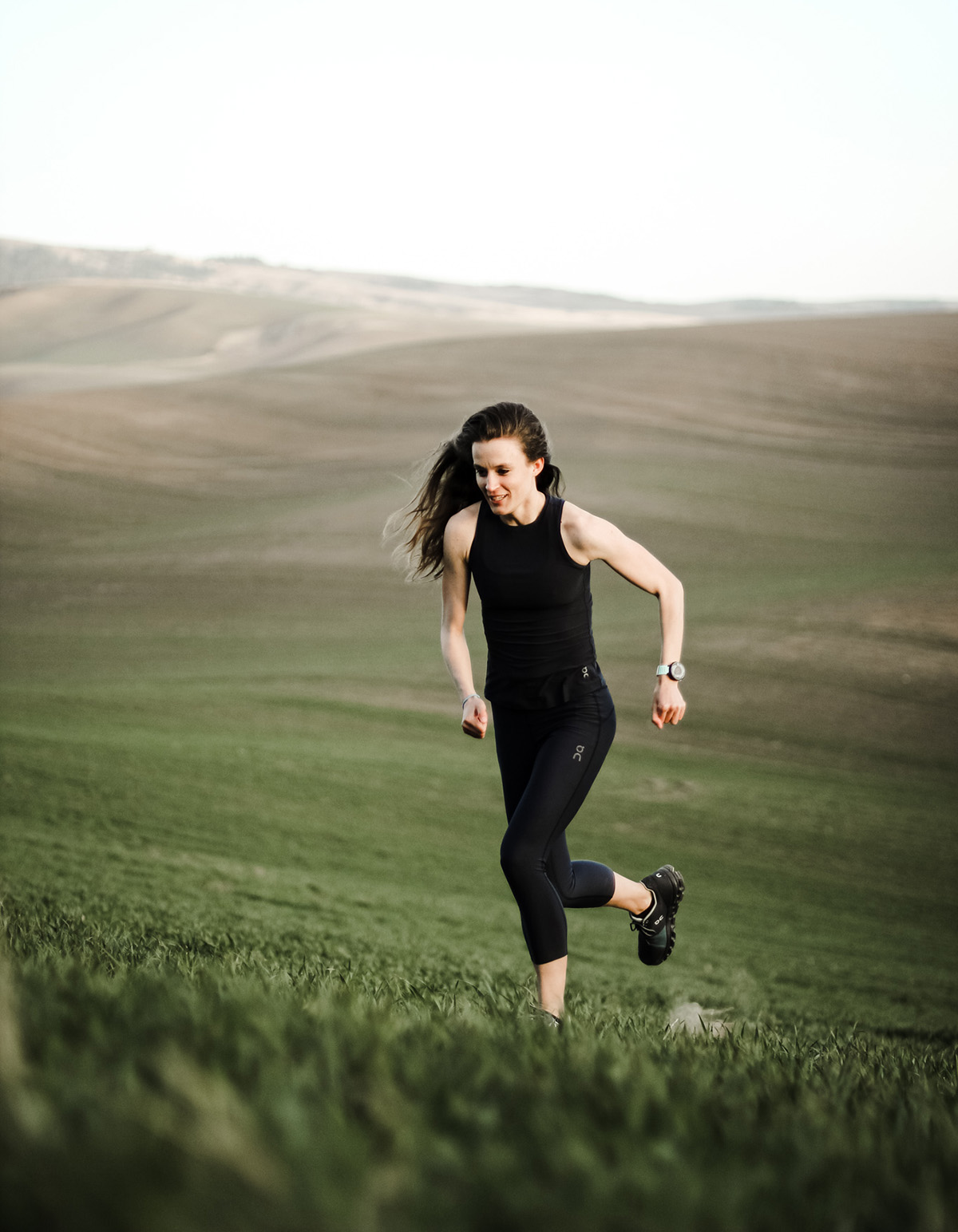 Woman in black running on green hills