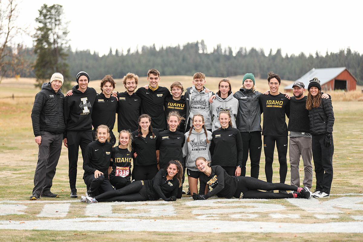 Photo of athletic team posing with barn and trees in background