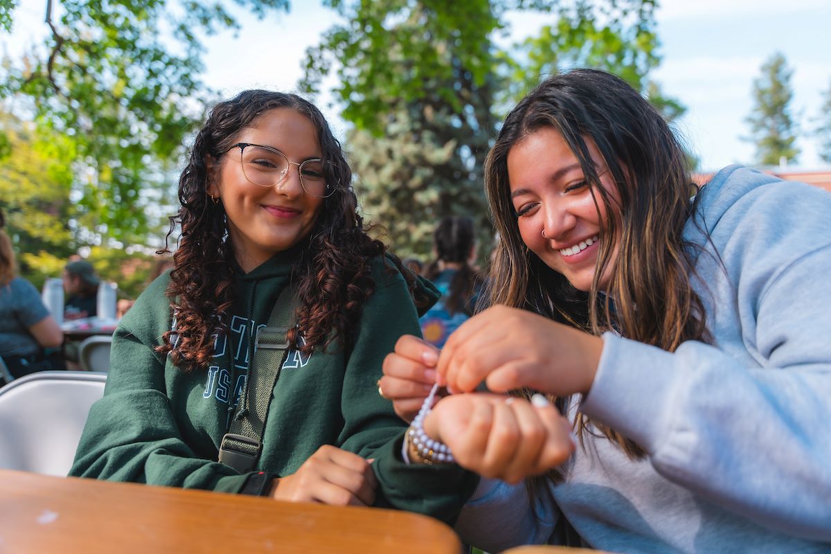 Two UIdaho students giving each other friendship bracelets