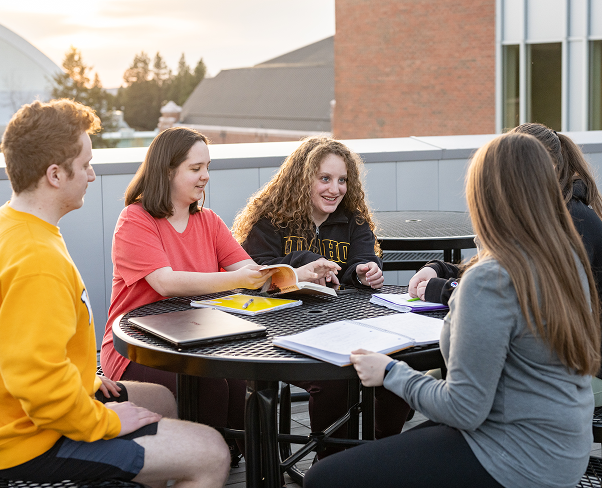 Five students sitting at a table outside.