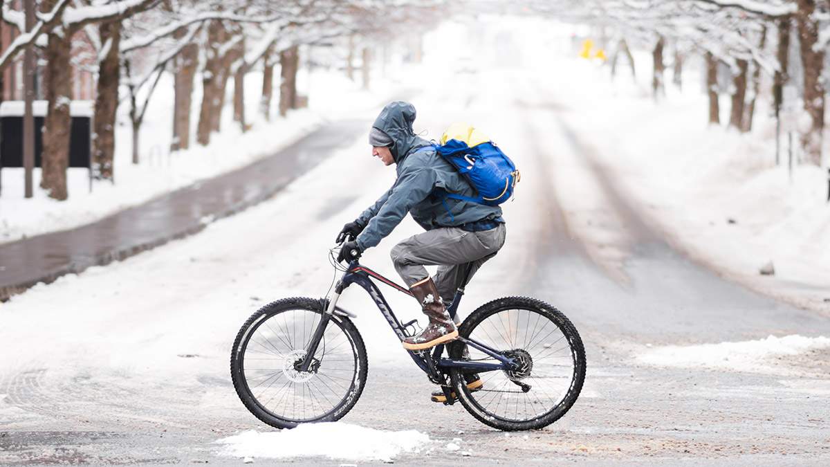 A student riding a bike in the snow on U of I's campus