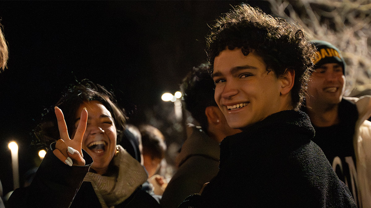 One student smiling at the camera, while the other is holding a "peace-sign"