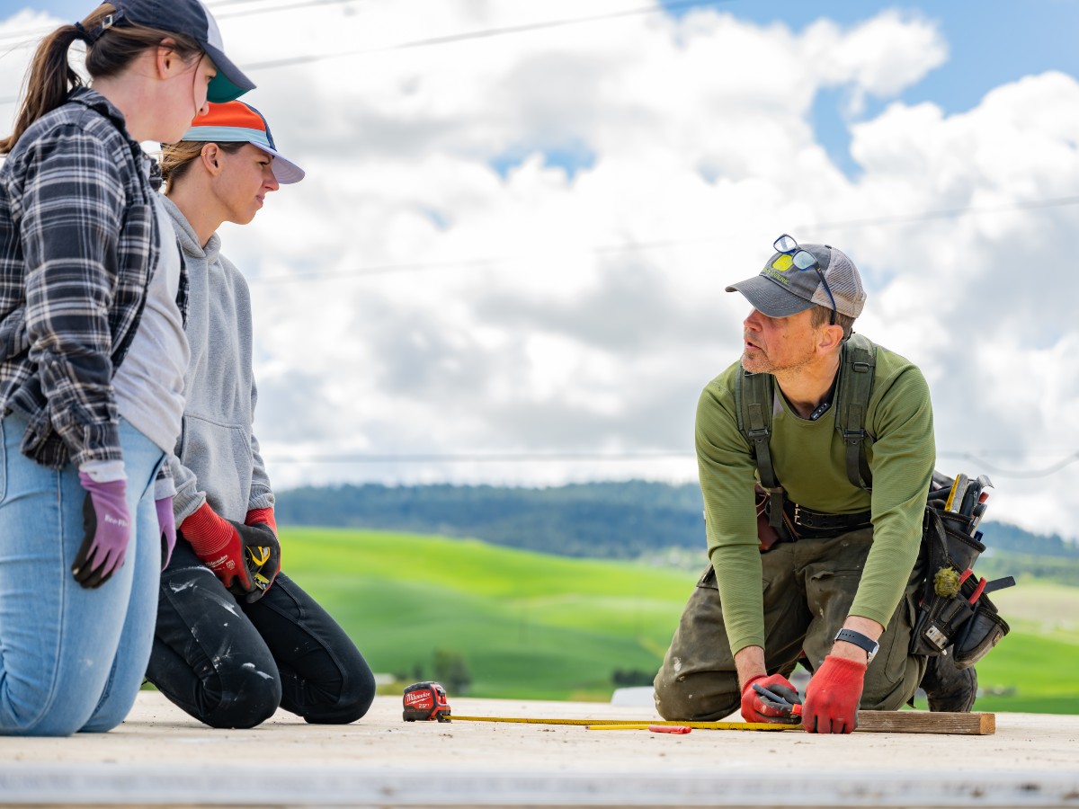 Three people working on house construction.