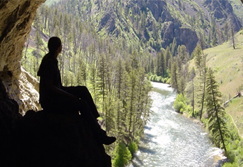 Student sitting on a rock looking over the river at Taylor Ranch