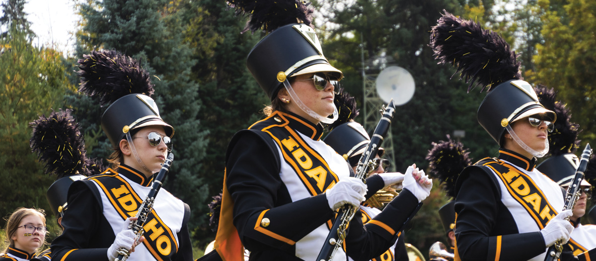 A close up image of three clarinet players in marching uniforms during a marching band performance.
