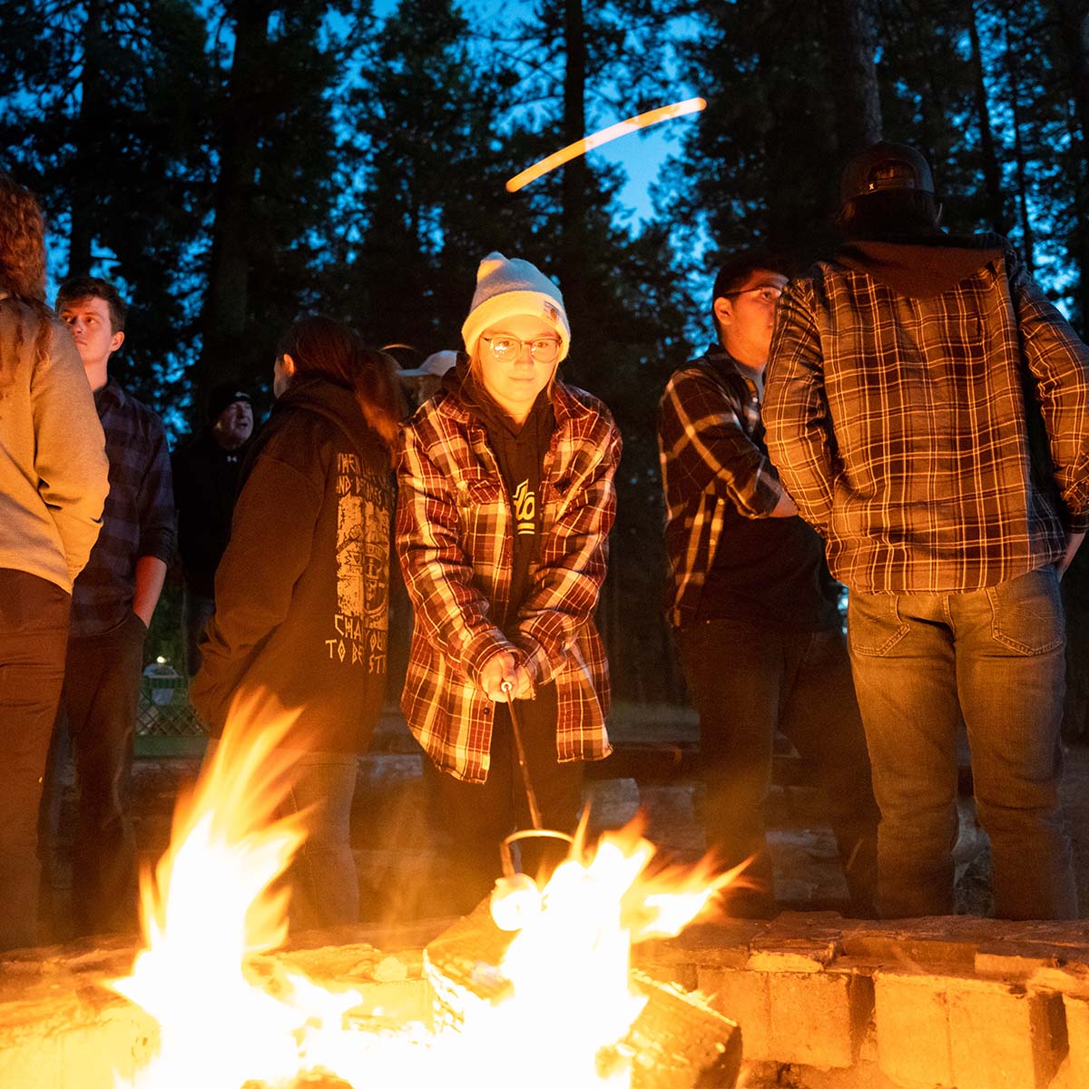 Student roasting marshmallows over campfire.