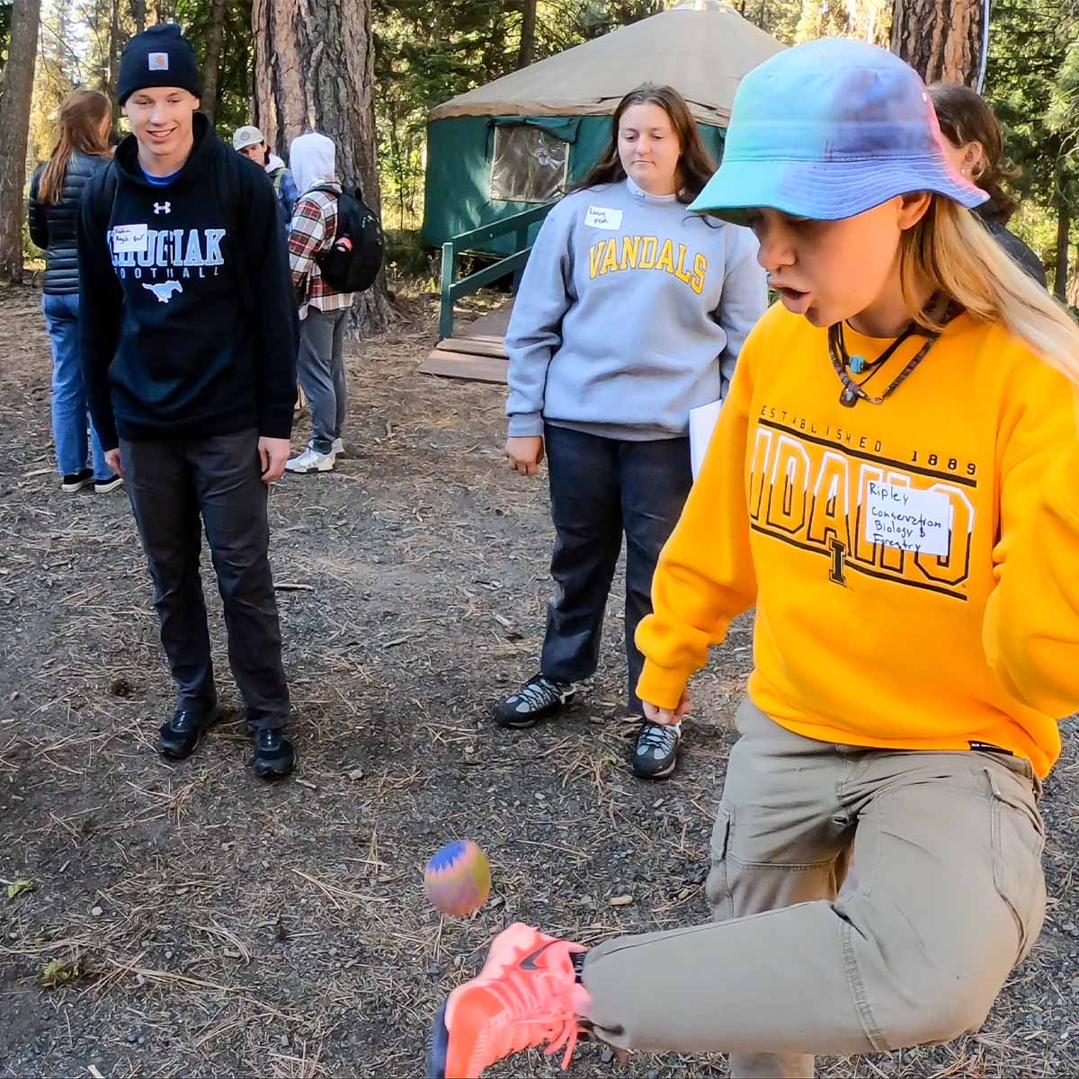 Four people play hackey sack.