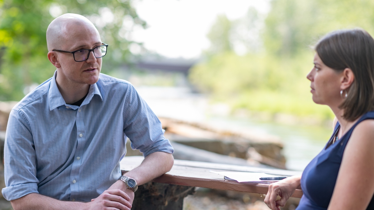 Mike Reynolds sits with Lindsay Lodis at a bench in a park.