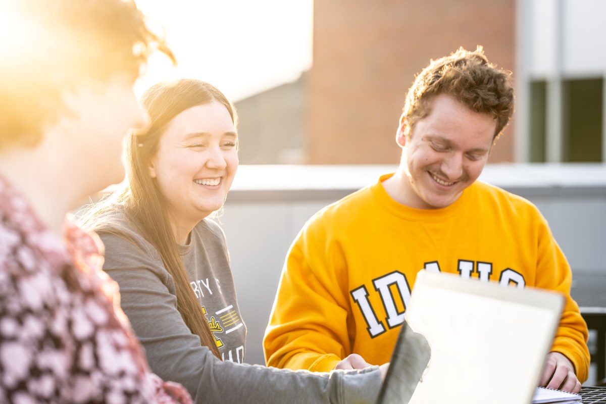 Three Vandal students studying on a patio on UIdaho campus.
