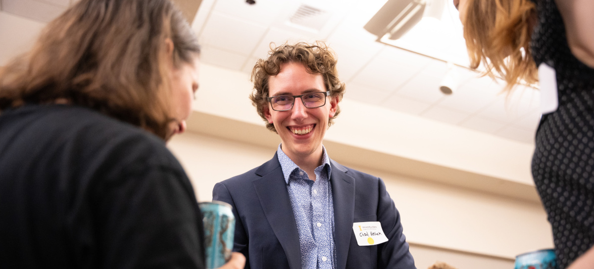 A student wearing professional attire smiles while showing their application materials to an employer.