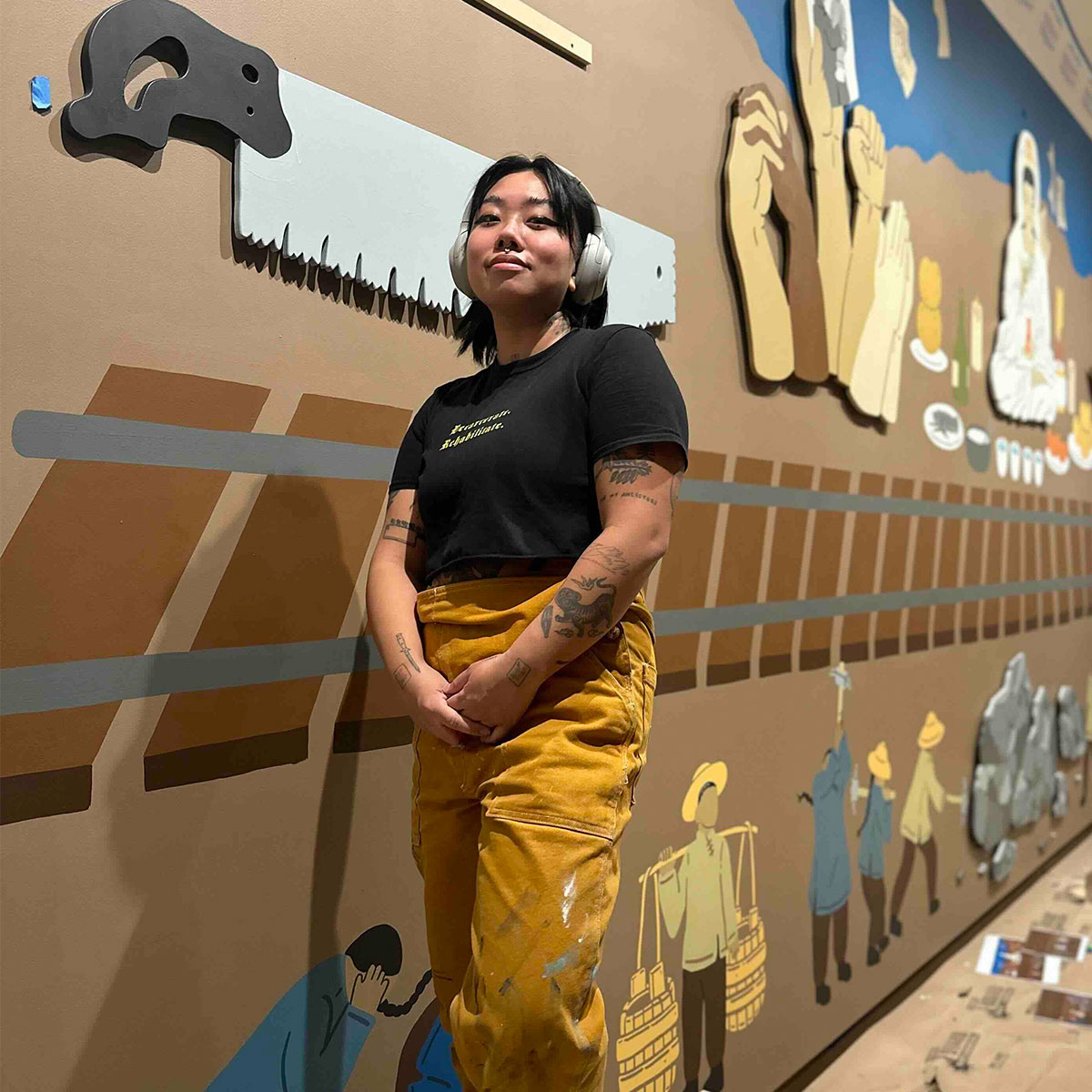 Monyee Chau standing in front of a wall full of cultural art