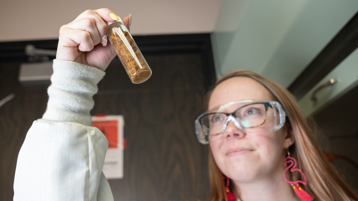 Woman holds beaker of dirt