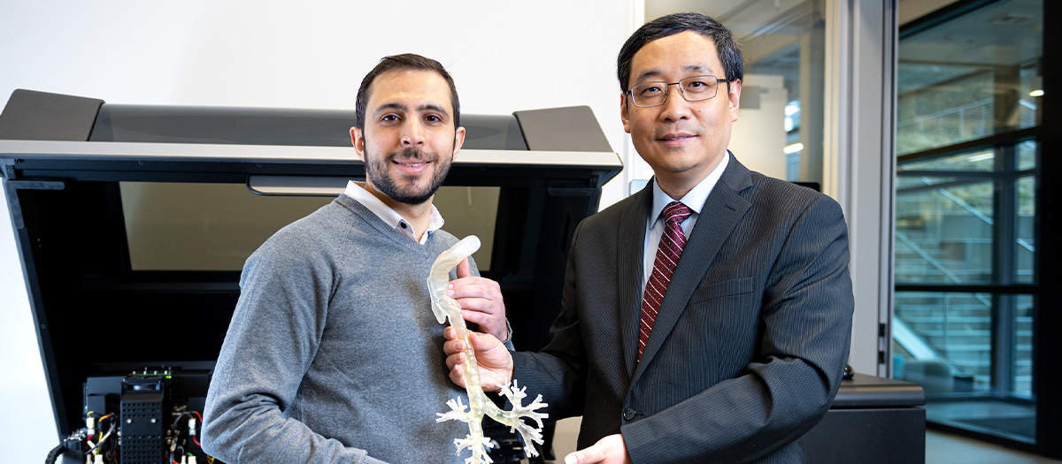 Dr. Xing with an associate displaying a 3-d printed object in a lab.