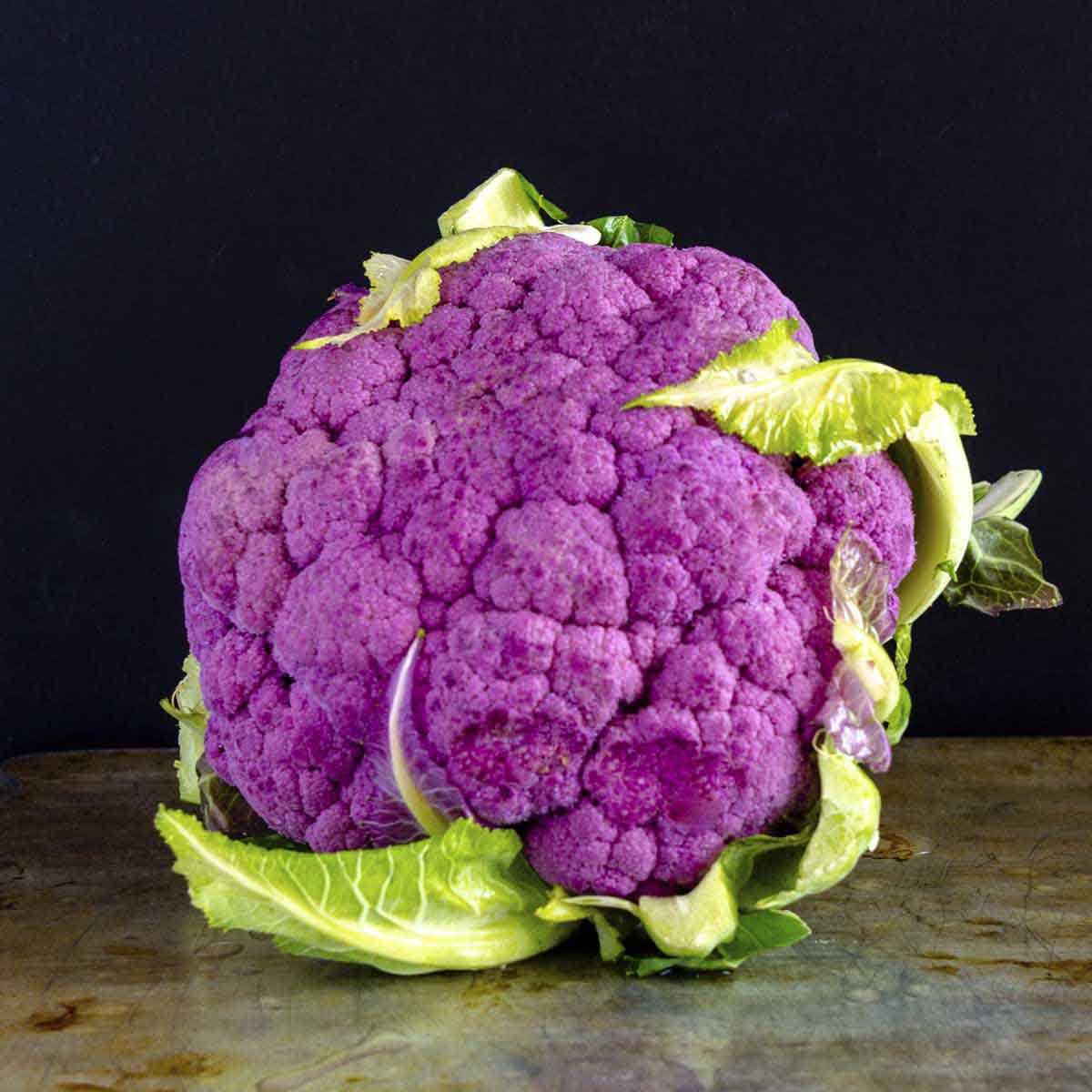 Purple cauliflower head on table.