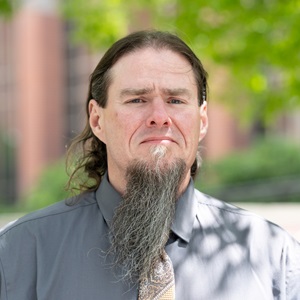 With long hair and a long beard, Dale looks at the camera for a photo.