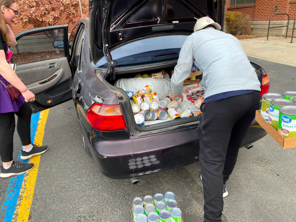 Students unloading canned food from car trunk.