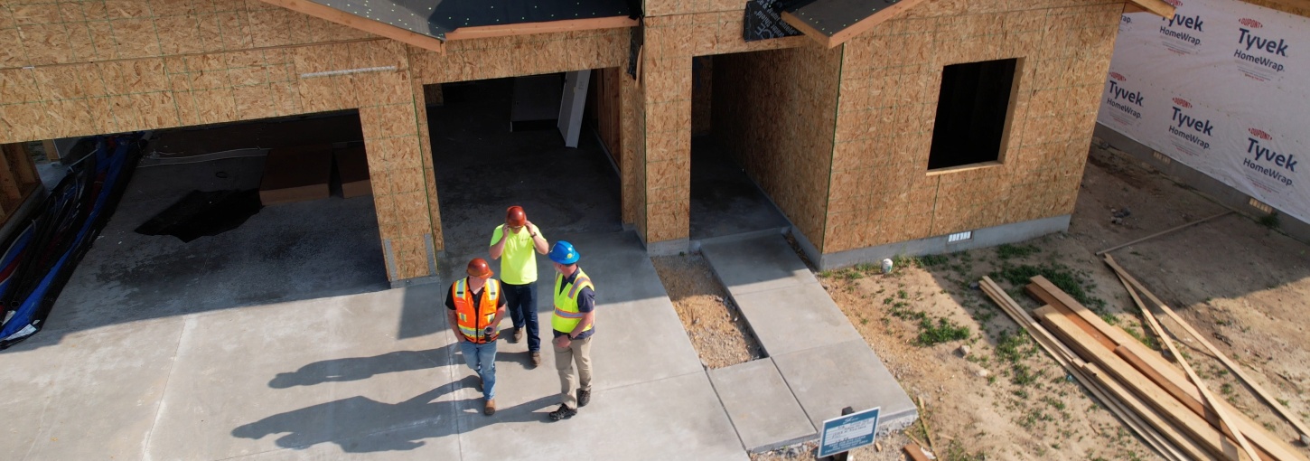 Birds eye view of construction workers in front of a newly constructed house.