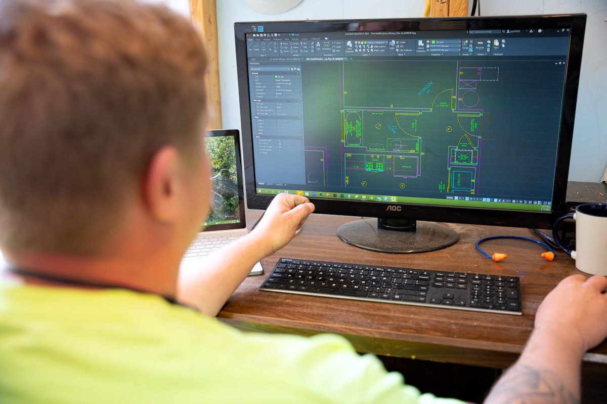 Person sitting at computer, monitor showing floorplan of a house.