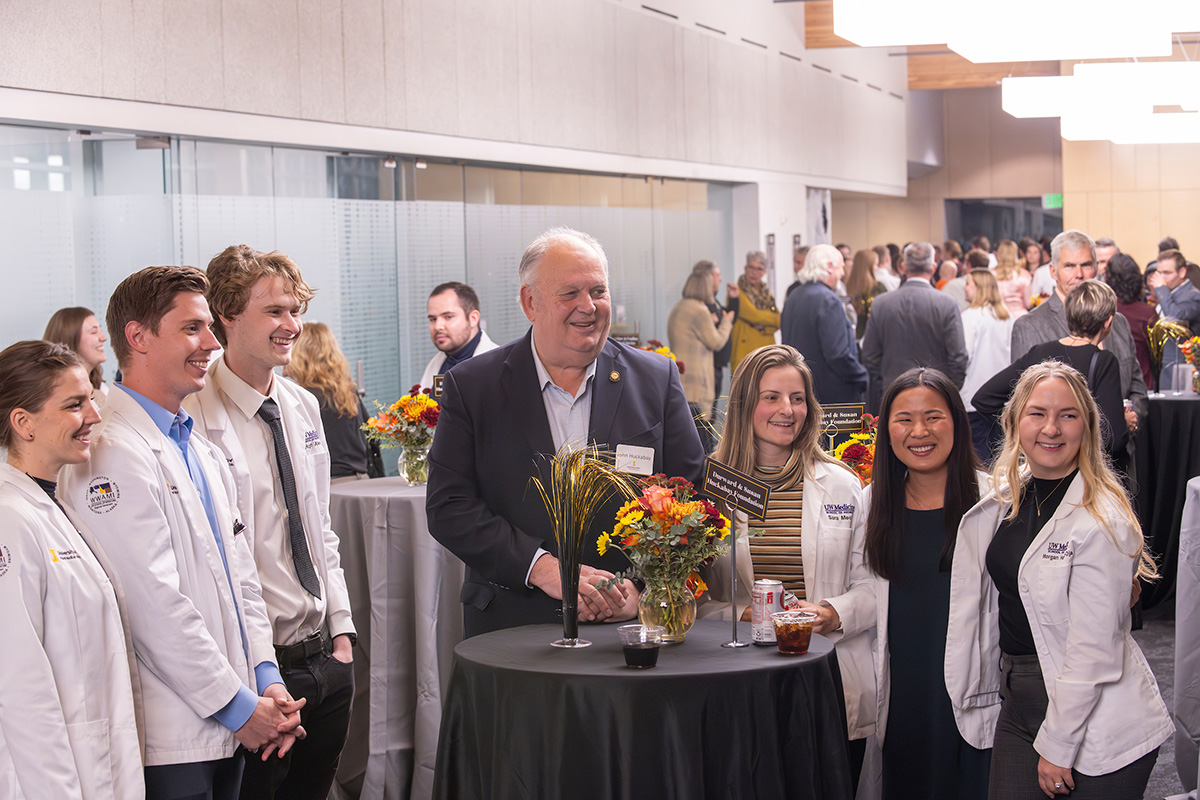 John Huckabay conversing with students in white coats.