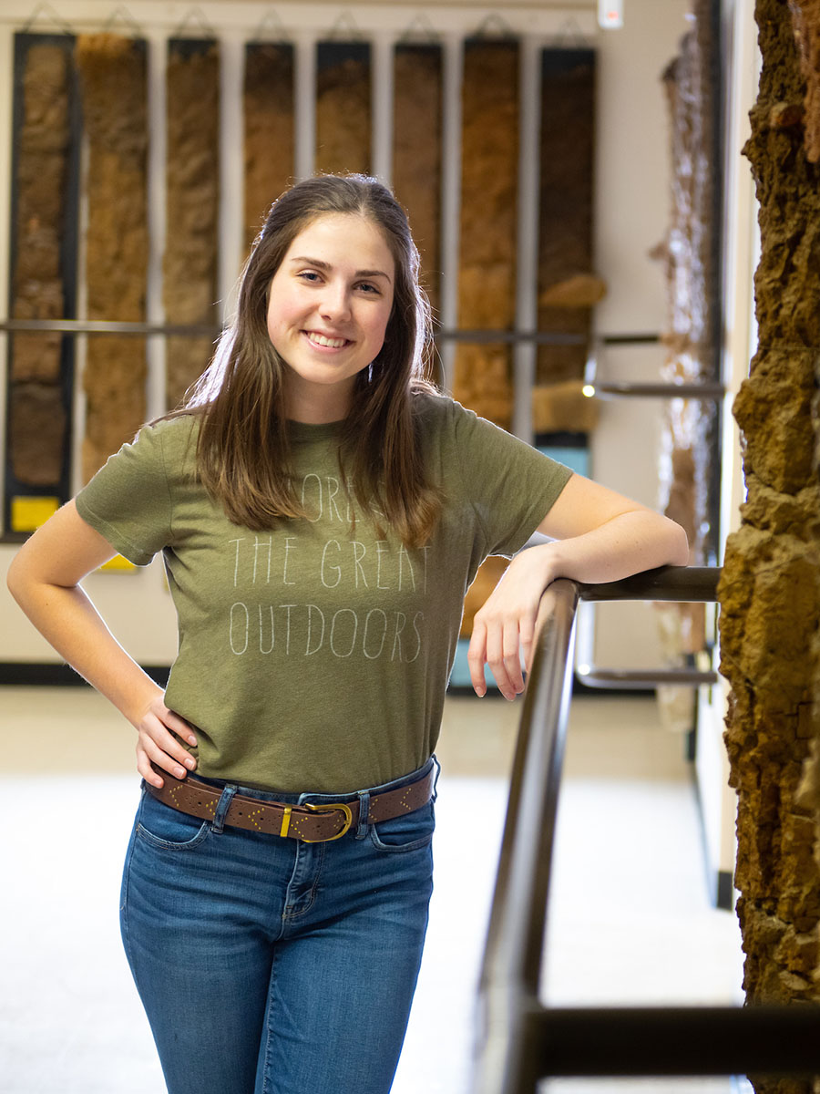 Woman stands in hallway next to soil monoliths. 